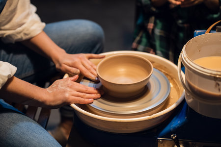 a young female potter teaches a small boy to make a pot of clayの写真素材