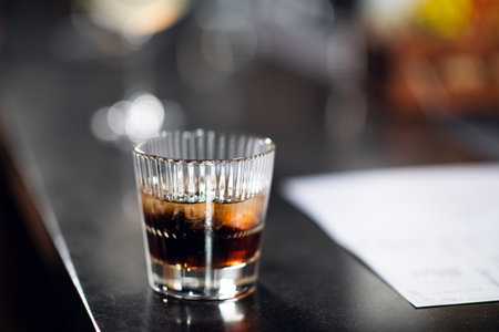 a glass of whiskey with ice on the bar close up.の写真素材