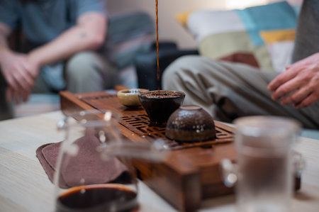 Mens hands pour fragrant amber tea into a glass bowl. Tea ceremony and tasting in traditional chinese styleの写真素材