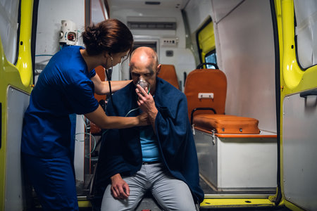 A paramedic examining a man rescued from the fire in an ambulance car.の写真素材