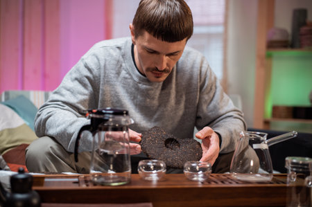 A man in an intimate home environment prepares for a Chinese tea ceremony, inhales the aroma of fresh raw black teaの写真素材