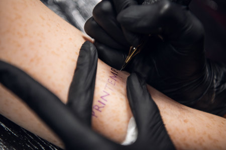 Close-up stick and poke method of tattooing a young girls hand with the inscription in French...
