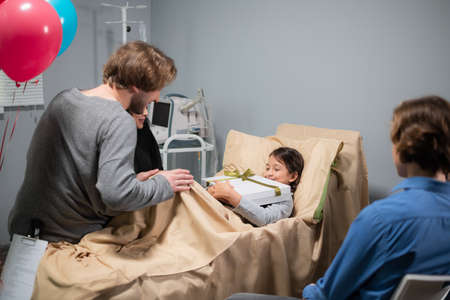 A birthday party in a hospital ward, a smiling, little girl is receiving presents.の写真素材