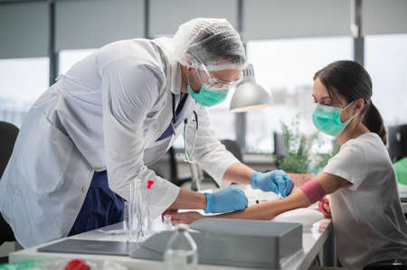 A medical student takes blood from a vein for analysis from a young woman in a laboratory.の写真素材