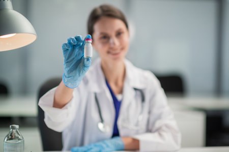 In the treatment room of the hospital, a nurse is preparing to vaccinate the population against , holding a vaccine in her hand.の写真素材