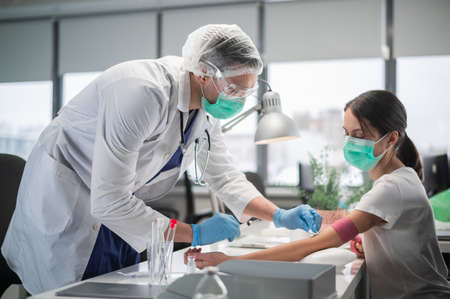 A young woman came to the laboratory to donate blood from a vein, a young laboratory assistant takes blood.の写真素材