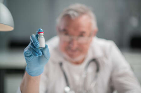 The new   vaccine is in a glass ampoule in the hands of a knowledgeable doctor. Mockup for placing a product with a blurred background.の写真素材