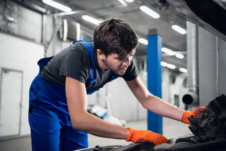 A mechanic in gloves replaces the engine of a carの写真素材