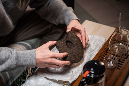 A man prepares raw ripe tea for a tea ceremony. Picks out a piece of tea with a tea needle. Hands close-up.の写真素材