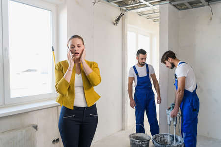 Inspector calls on the phone, workers knead plasterの写真素材