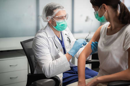 In a medical laboratory, a young woman is vaccinated against coronavirus during a pandemicの写真素材