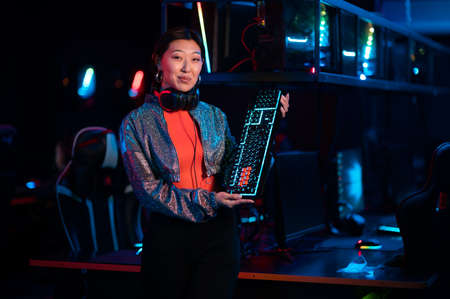 An experienced esports girl advertises a new gaming keyboard in the neon lightの写真素材