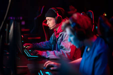 A multi-racial team of esports athletes conducts a training session before an online shooter tournament. Neon light.の写真素材