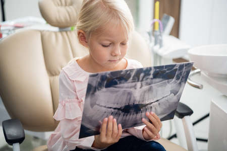 Close up of a cute little female child examining an x-ray of a jの写真素材