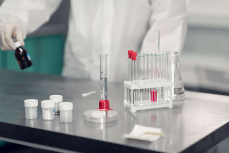 A scientist working in a chemical laboratory. Laboratory equipment and glassware containing chemical liquids in the foregroundの写真素材