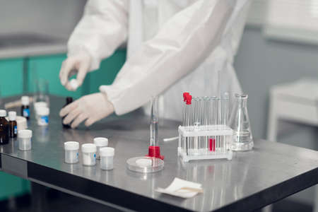 Close-up of a lab table with test tubes, liquids, glassware and other lab equipmentの写真素材