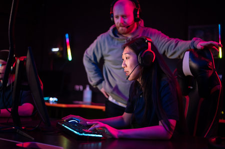 Individual training sessions with an esports coach in a computer club, an asian girl plays dotaの写真素材