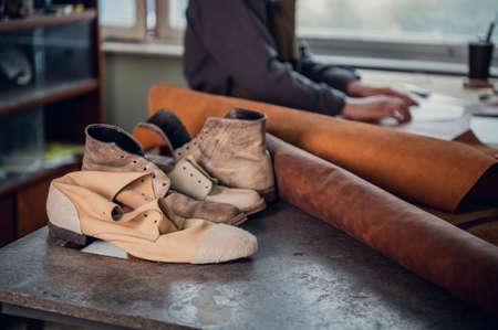 Experienced specialist in the production of footwear leather lays on a table in his workshopの写真素材