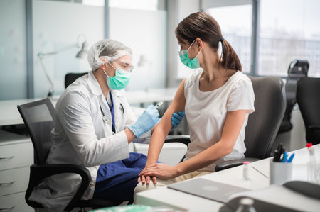 A young medical student injects a coronavirus vaccine into a young girls shoulderの写真素材