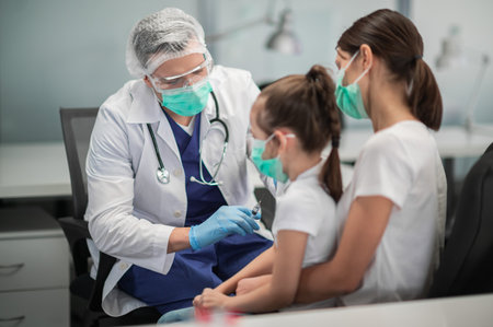 A caring mother brought her daughter to the vaccination office to get vaccinated, the girl is afraidの写真素材
