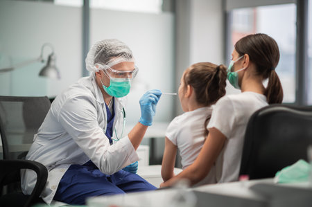 Mom brought her little daughter to the clinic to be tested for coronavirus, the doctor takes a smearの写真素材