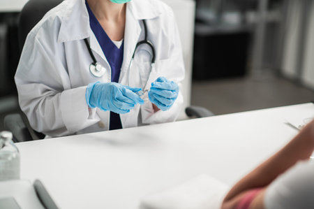 The nurse is preparing to inject the drug into the patients vein, holding a syringe with the drug in her handsの写真素材