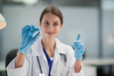 The doctor prescribes the medicine and presents the patient with its antiviral properties. A hand in a medical glove in the foregroundの写真素材