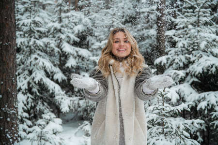 An incredibly joyful beauty walks through a winter fairy-tale forest. Throws up flakes of snow. Portrait with depth of field.の写真素材