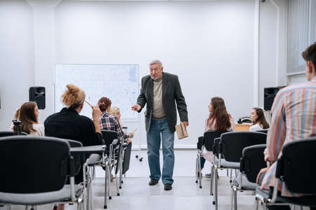 During a physics test in college, a professor in a jacket walks around the audience and communicates...