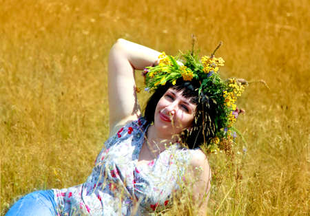 Happy smiling girl with a wreath of wildflowers on her head.の写真素材