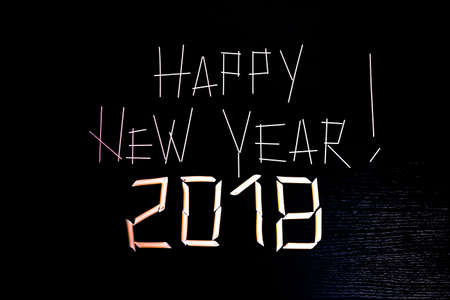 The Inscription Happy New Year! 2018 on the dark wooden surface with a touch of black made of pasta,...