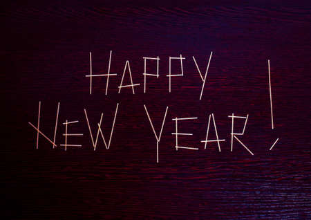 The inscription Happy New Year with an exclamation point on a maroon wooden surface with a slight tinge fioletovogo made of pastaの写真素材