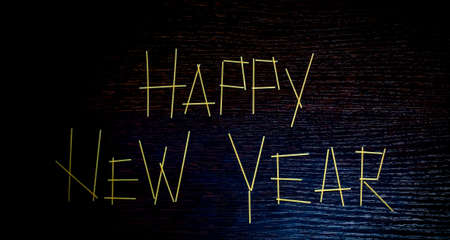 The inscription Happy New Year 2018 on a dark wooden surface with a blue light is made of pastaの写真素材