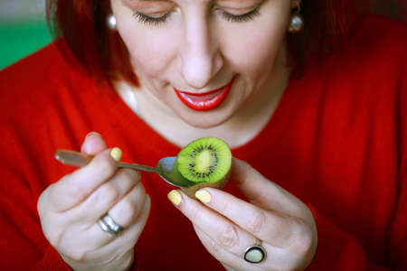 Beautiful young woman eating ripe and juicy fruit KIWIの写真素材
