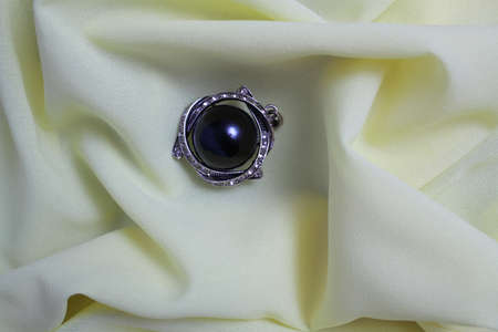On the crumpled silk fabric is a black female brooch decorated with cubic Zirconiaの写真素材