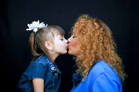 On a black background mother and daughter kissing. They love each other and are very happy.の写真素材