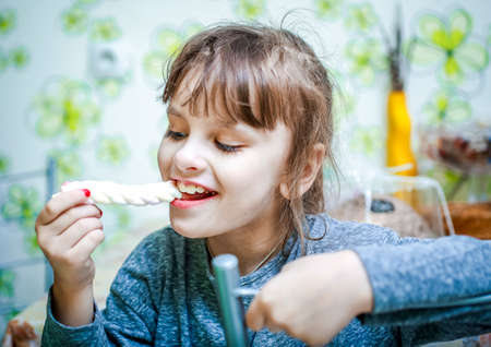 Cute beautiful little girl eating chewing candyの写真素材