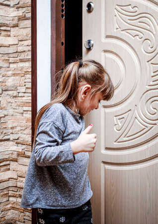 A little girl walks into the apartment and closes the doorの写真素材