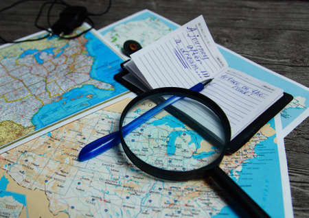 On the table is the us Atlas close-up, magnifying glass, notebook and pen. A man is going on a journey.の写真素材
