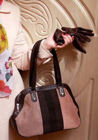 A female figure with a bag in his hand and removed gloves is in the hallway.