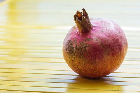 A pomegranate on the table in front of a windowの写真素材