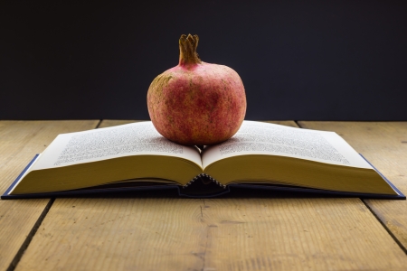 Book with a pomegranate on the wooden table の写真素材