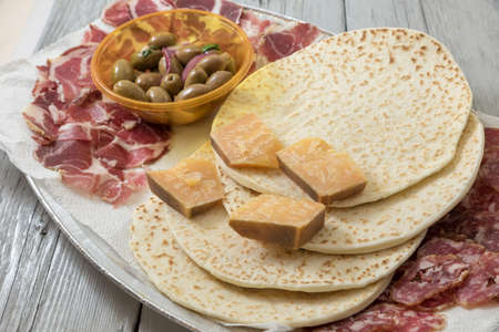 Romagna piadina with salami, cheeses and olivesの写真素材