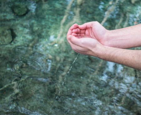 Sunny day of the person with crystal lake water falling from handsの写真素材