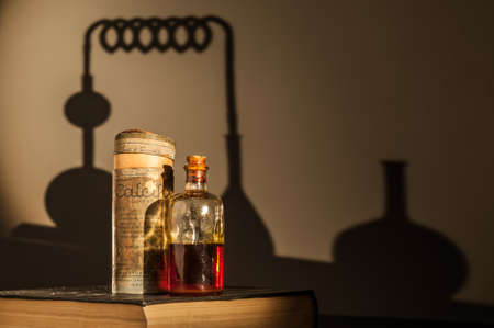 Old bottle containing some kind of drug, on a bookの写真素材