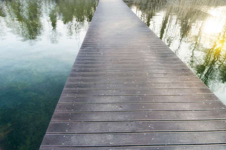 Infinity long pedestrian bridge over a lake with reflectionsの写真素材