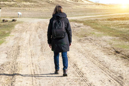 Stock Foto Caucasian man in black coat arms raised on empty road towards sunset horizontalの写真素材