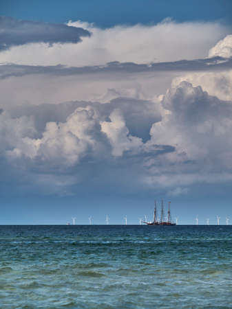 Two possibilities of using wind energy: sailing boat before a wind farm in the Baltic sea, Germany