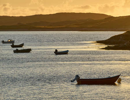 Boats at sunset in a lonely bay of Connemara, Irelandの写真素材