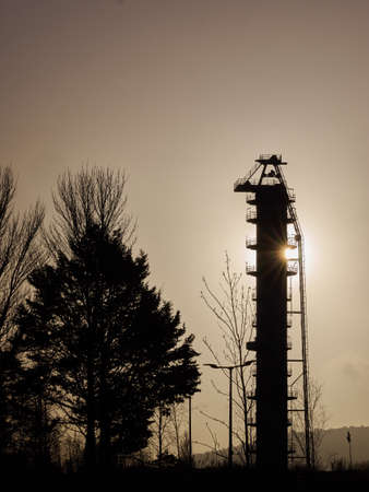 Sun behind a factory tower